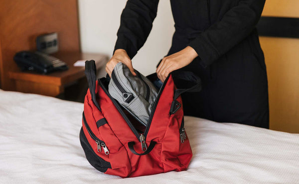 Person pulling a Packing Cube Shoulder Bag out of the main compartment of the OSCA.